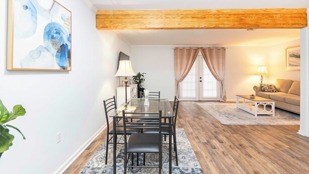 A dining area with a glass table and chairs, a wooden ceiling, a sofa, and a lamp. - Cozy townhouse minutes from Downtown Lafayette, LA (Lafayette)