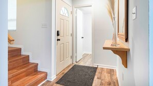A hallway with wooden stairs, a door with a window, a dark rug, and a wooden shelf with a vase. - Cozy townhouse minutes from Downtown Lafayette, LA (Lafayette)
