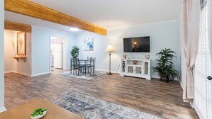 A spacious living room with a wooden ceiling, a dining area, and a television mounted on the wall. - Cozy townhouse minutes from Downtown Lafayette, LA (Lafayette)