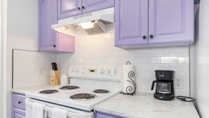 A kitchen with white and purple cabinets, a white stove, and a coffee maker. - Cozy townhouse minutes from Downtown Lafayette, LA (Lafayette)
