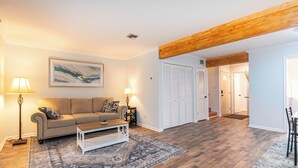 A living room with a sofa, coffee table, and lamps. There is a wooden beam on the ceiling and a door leading to another room. - Cozy townhouse minutes from Downtown Lafayette, LA (Lafayette)