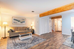 A living room with a sofa, coffee table, and lamps. There is a wooden beam on the ceiling and a door leading to another room. - Cozy townhouse minutes from Downtown Lafayette, LA (Lafayette)