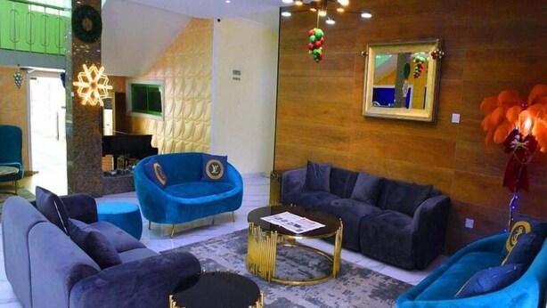 A modern living room with a blue sofa, a grey sofa, and a blue armchair. There is a gold-framed coffee table in the center. - The Dover Hotel Lekki (Lekki)