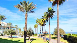 Ein gepflegter Garten mit Palmen, einer Laube und Blick auf das Meer.