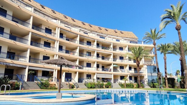 Un hotel de varios pisos con piscina, balcones y palmeras.