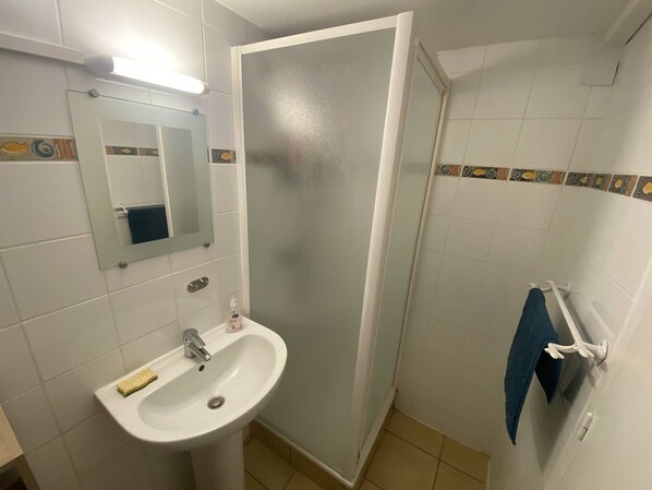 Ein Badezimmer mit Waschbecken, Spiegel und Duschbereich.
