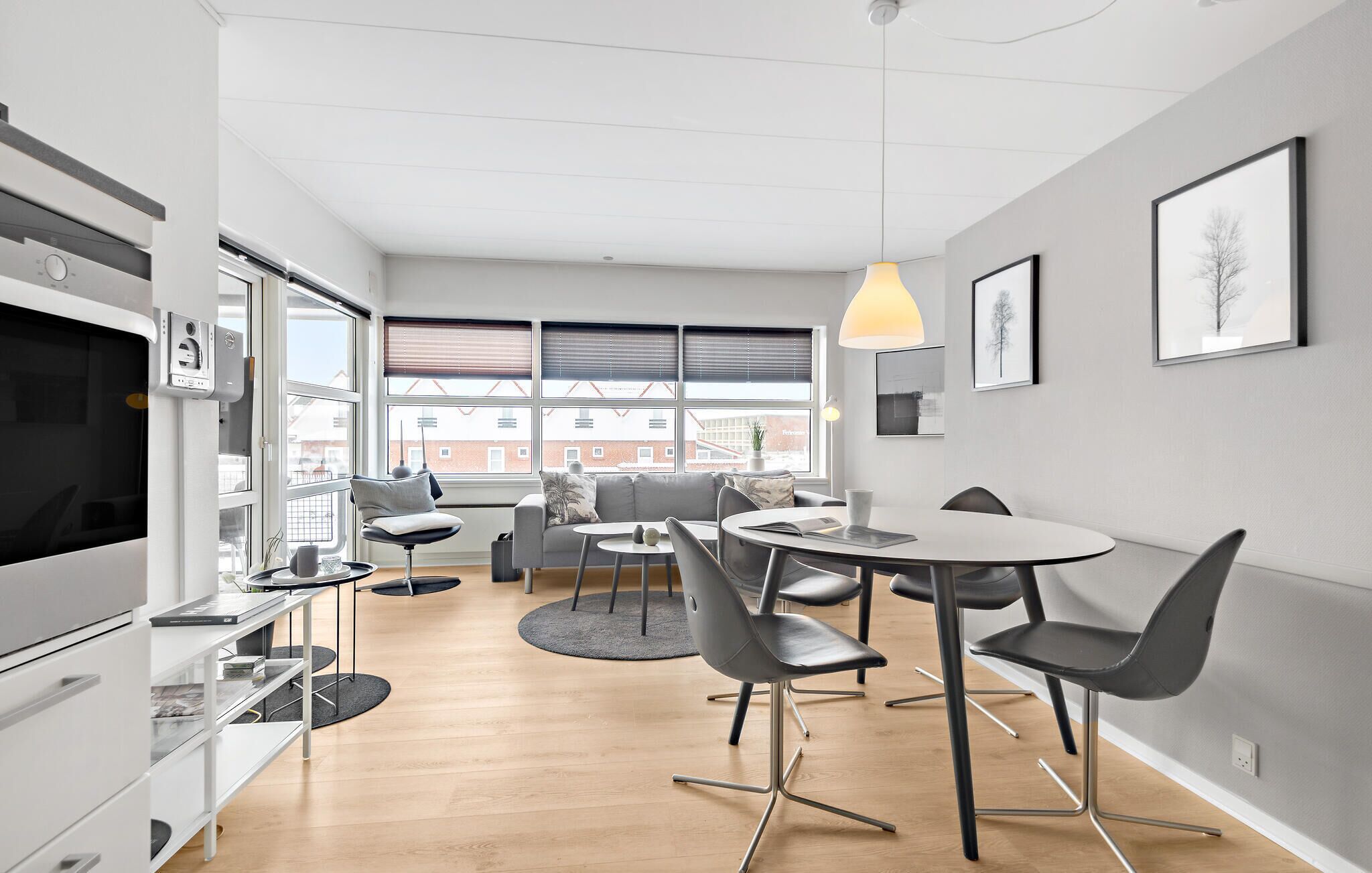 Une pièce moderne et bien éclairée, comprenant un coin repas, un canapé et un téléviseur.