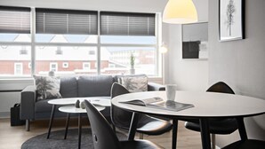 Un soggiorno moderno con un divano grigio, due tavolini rotondi e una lampada a sospensione.