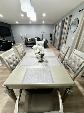 A dining area with a rectangular table, six chairs, and a vase with white flowers.