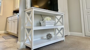 A white wooden TV stand with a flat-screen TV, a decorative item, and a small white box. - New, Clean, Downtown Getaway! (Concord)