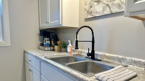 A kitchen with two stainless steel sinks, a black faucet, a dish soap bottle, and a dish drying rack. - New, Clean, Downtown Getaway! (Concord)