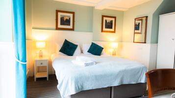 A hotel room with a bed, two bedside tables with lamps, a chair, and a wardrobe.