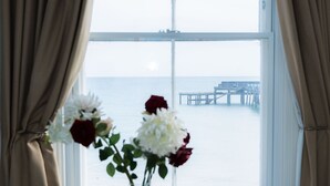 Una stanza con un tavolo rotondo bianco, un vaso con fiori e vista sul mare attraverso un'ampia finestra.