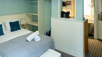 A hotel room with a bed, a small desk, a mirror, and a bathroom visible through an open door.
