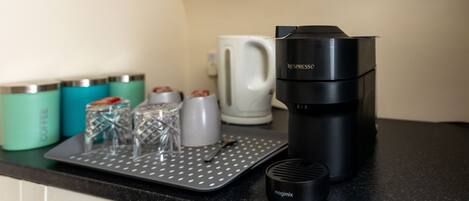 A kitchen counter with a coffee maker, a mug, and a tray with glassware.