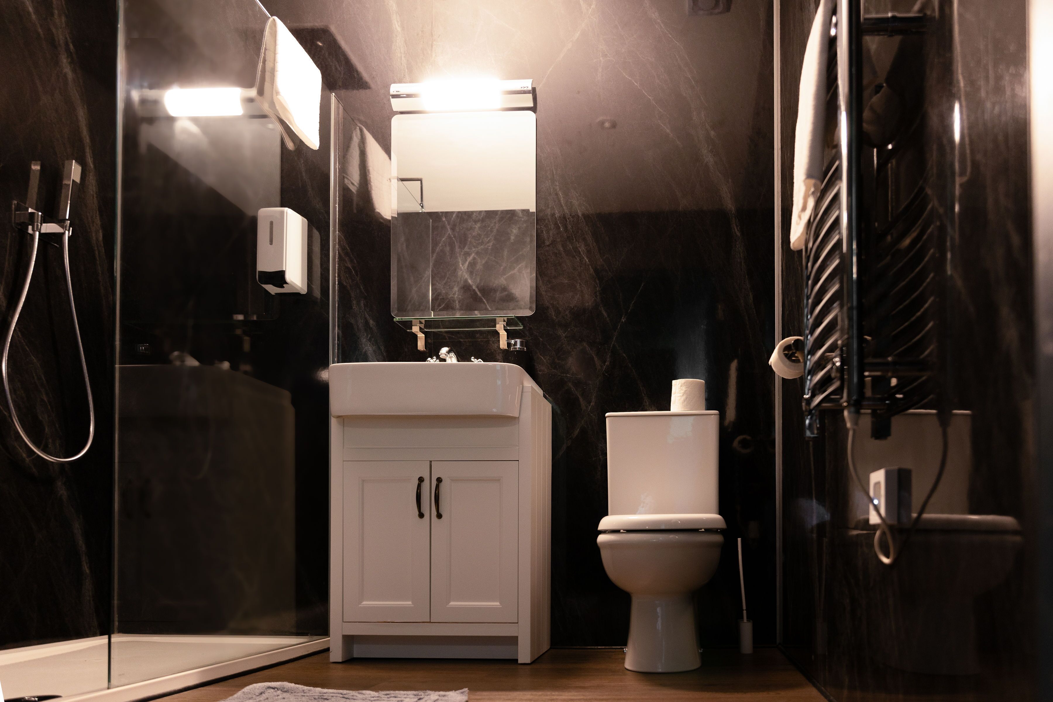 A modern bathroom with a glass shower enclosure, a white vanity with a mirror, and a toilet.