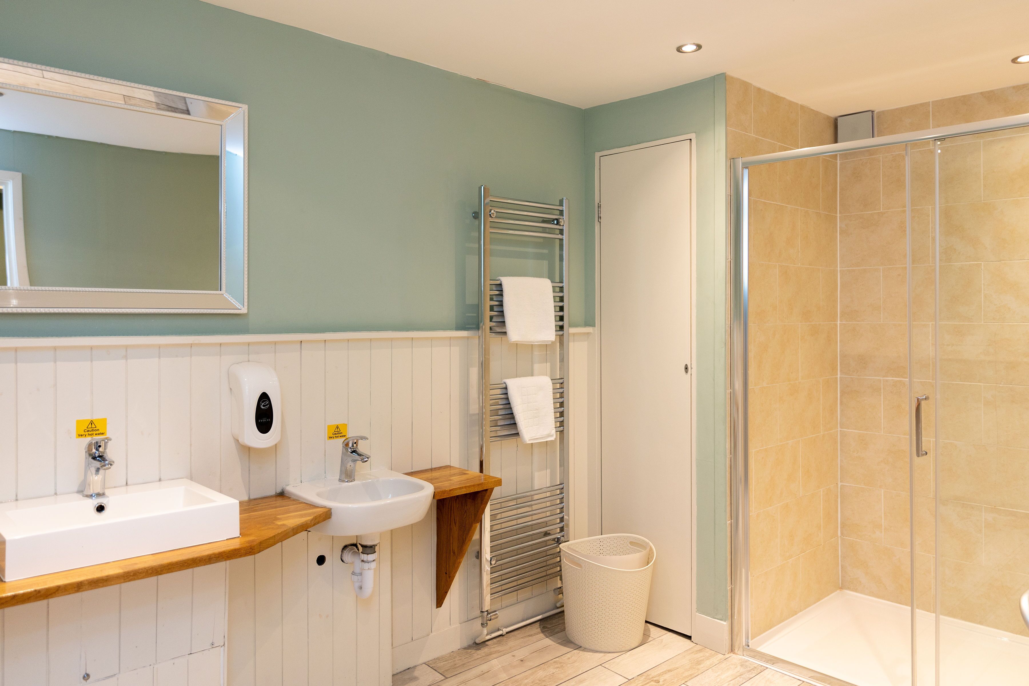 A bathroom with a wooden vanity, a sink, a mirror, a towel rack, and a glass-enclosed shower.