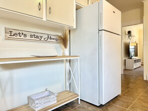A kitchen with a white refrigerator, a wooden table with a plate and a vase, and a sign above the table that reads "Let's stay home". - Spacious 3 Bedroom 2 Bath First Floor Apt Close to Downtown Concord (Concord)