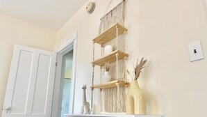 A white door, a macrame wall hanging, a wooden shelf, and a vase with dried plants. - Spacious 3 Bedroom 2 Bath First Floor Apt Close to Downtown Concord (Concord)