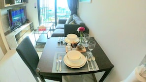 A dining area with a table set for four, including plates, bowls, cutlery, and glasses. A flower vase and a decorative bowl are on the table.