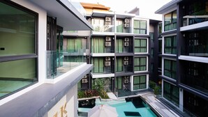 A modern multi-story building with balconies, a central courtyard with a pool, and large windows. - Bo202- 1 Bedroom Condo With Sea View Ao Nang Beach (Krabi)