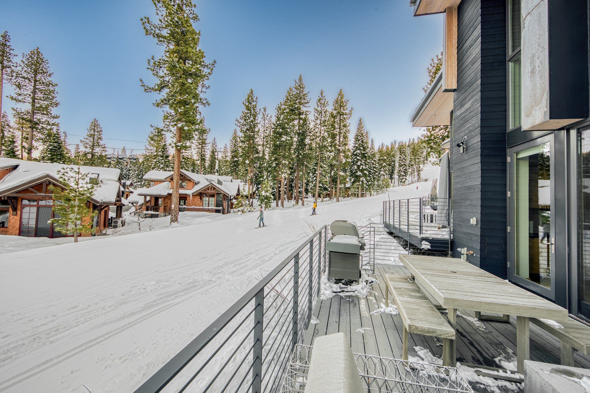 A snow-covered ski resort with wooden cabins and a modern building with large windows.