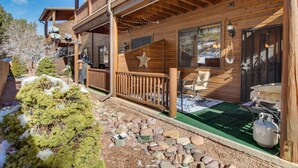 A wooden cabin with a balcony, a star decoration, and a stone pathway leading to the entrance.
