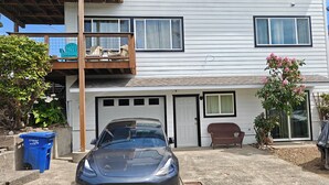 Ein zweistöckiges Haus mit Garage, einem Balkon mit Gartenmöbeln und einem geparkten Auto davor.