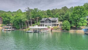 Une propriété située au bord de l’eau, comprenant une grande maison, un quai et des bateaux.