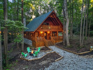 A log cabin with a porch, outdoor seating, and a fire pit. - Green Frog | Luxury Cabin in the Woods, Hot Tub (Logan)