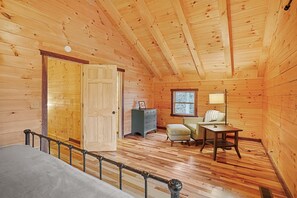 A log cabin interior with a wooden floor, a desk, a chair, a dresser, and a window. - Green Frog | Luxury Cabin in the Woods, Hot Tub (Logan)