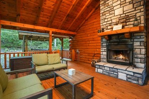 A cozy cabin with a stone fireplace, wooden deck, and a sofa.