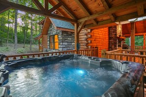 A wooden cabin with a hot tub and a stone fireplace. - Green Frog | Luxury Cabin in the Woods, Hot Tub (Logan)