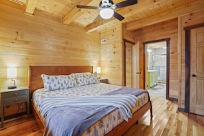 Un dormitorio con paneles de madera, una cama, mesitas de noche y un ventilador de techo.