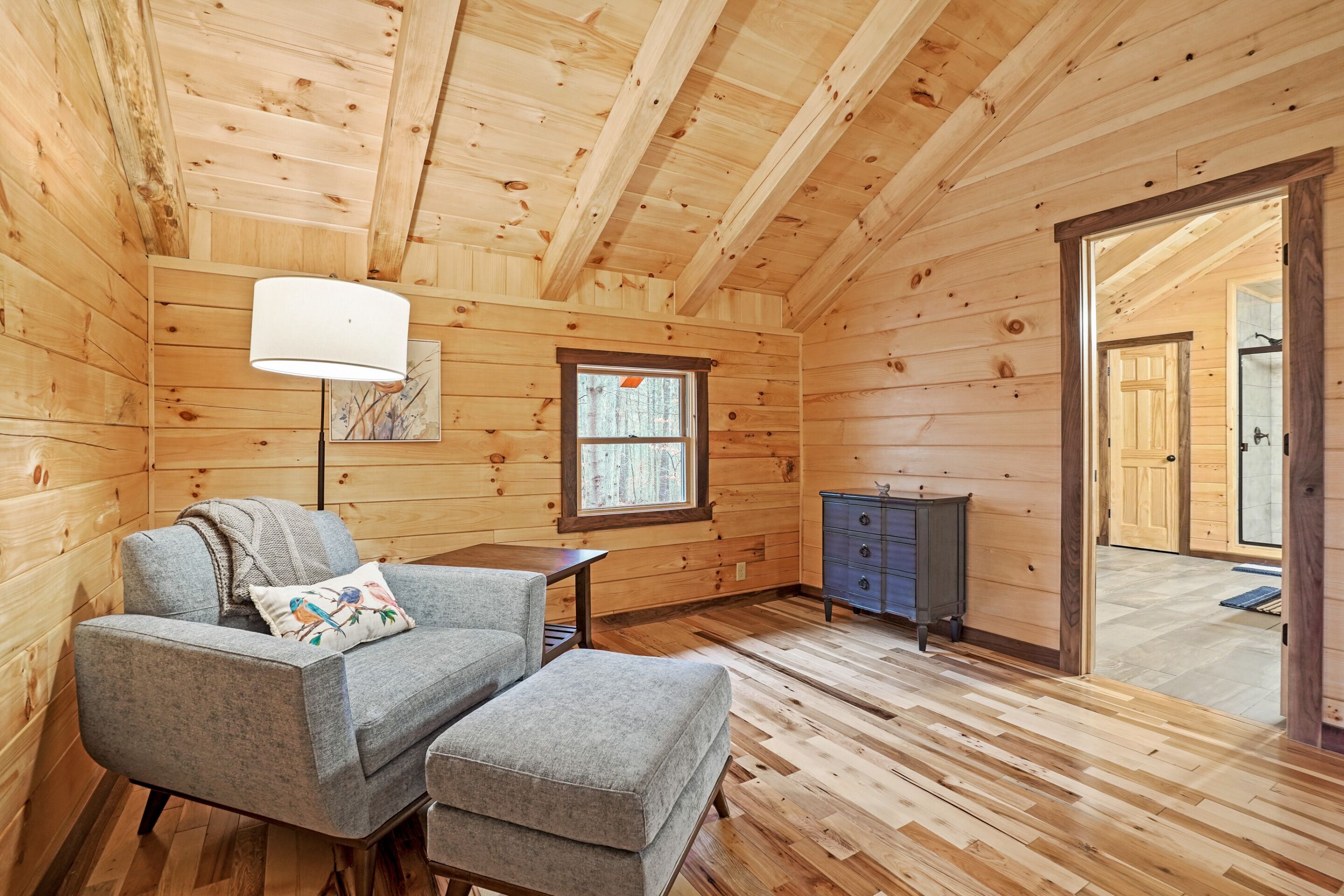 L’intérieur d’un chalet accueillant, avec un canapé, un pouf, une lampe et une commode.