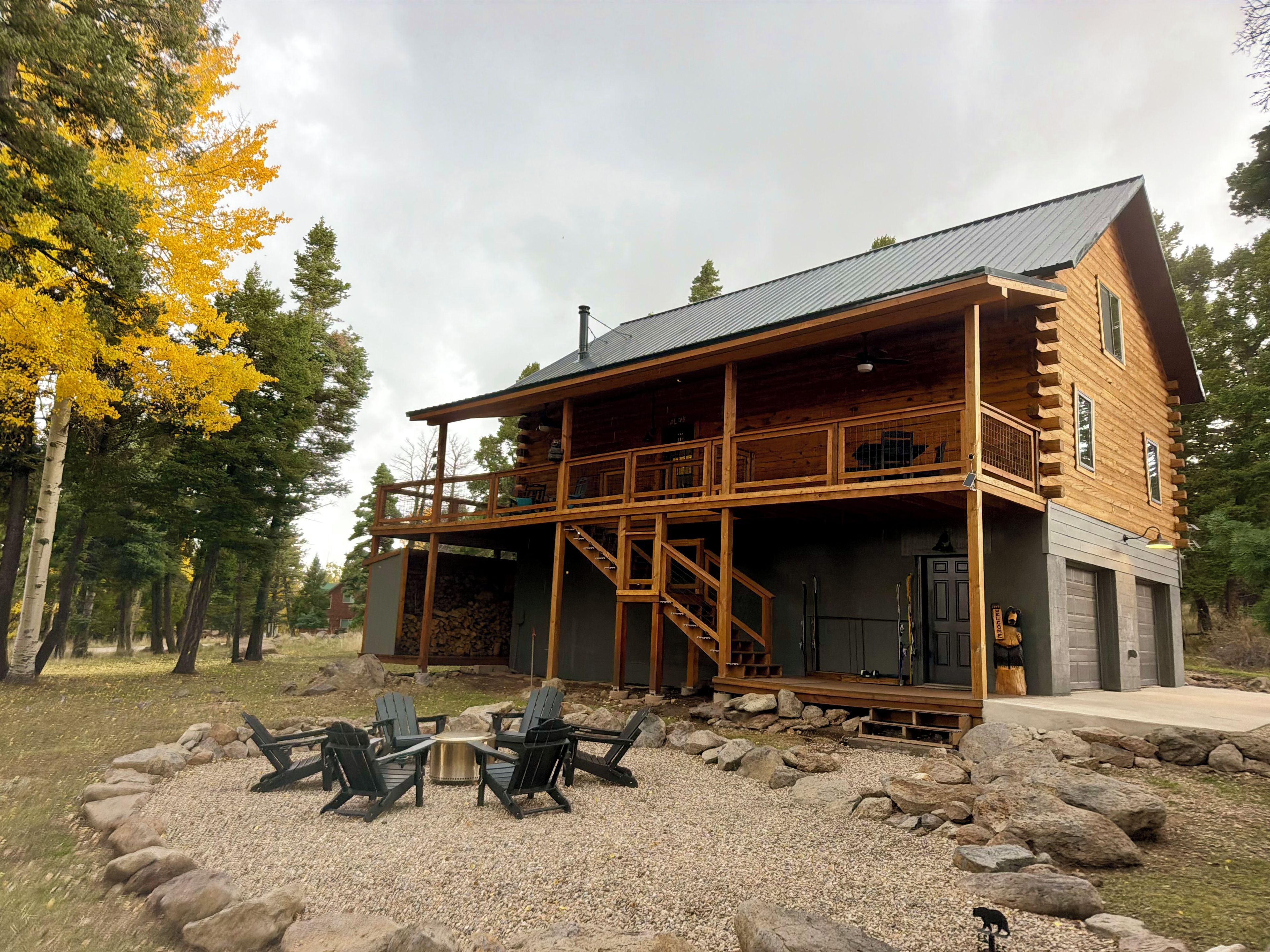A log cabin with a porch, outdoor seating, and a garage.