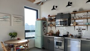 A modern kitchen with stainless steel appliances, wooden shelves, and a dining area with a table and chairs. - Gorgeous two bedroom with a huge terrace (Brooklyn)