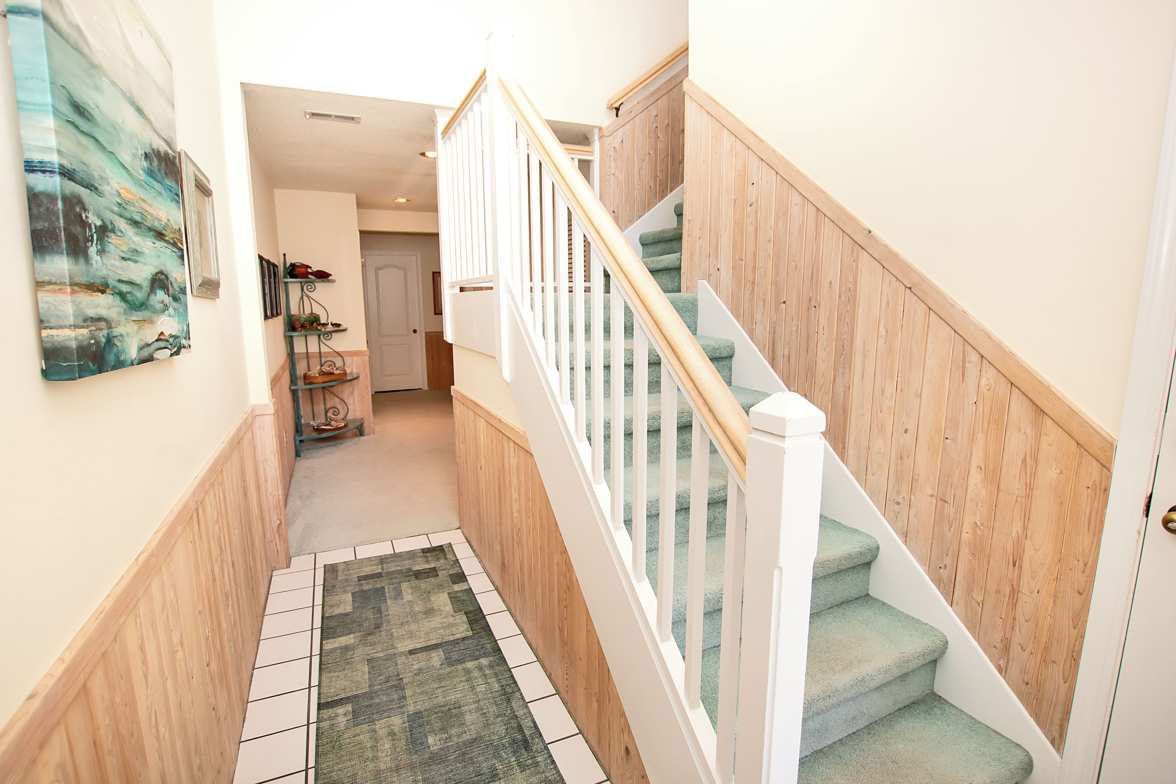 A staircase with wooden railings and carpeted steps leading to a door.