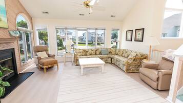 A spacious living room with a fireplace, a sectional sofa, a coffee table, and a ceiling fan.
