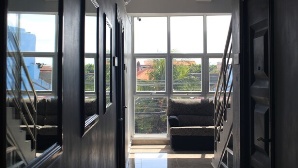 Un couloir avec de grandes fenêtres, un escalier et un canapé.