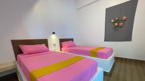 Une chambre d’hôtel avec deux lits, chacun agrémenté de draps roses et d’un élément décoratif jaune.