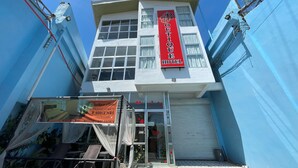 Un hôtel avec une enseigne rouge sur laquelle on peut lire « Hôtel de charme ».
