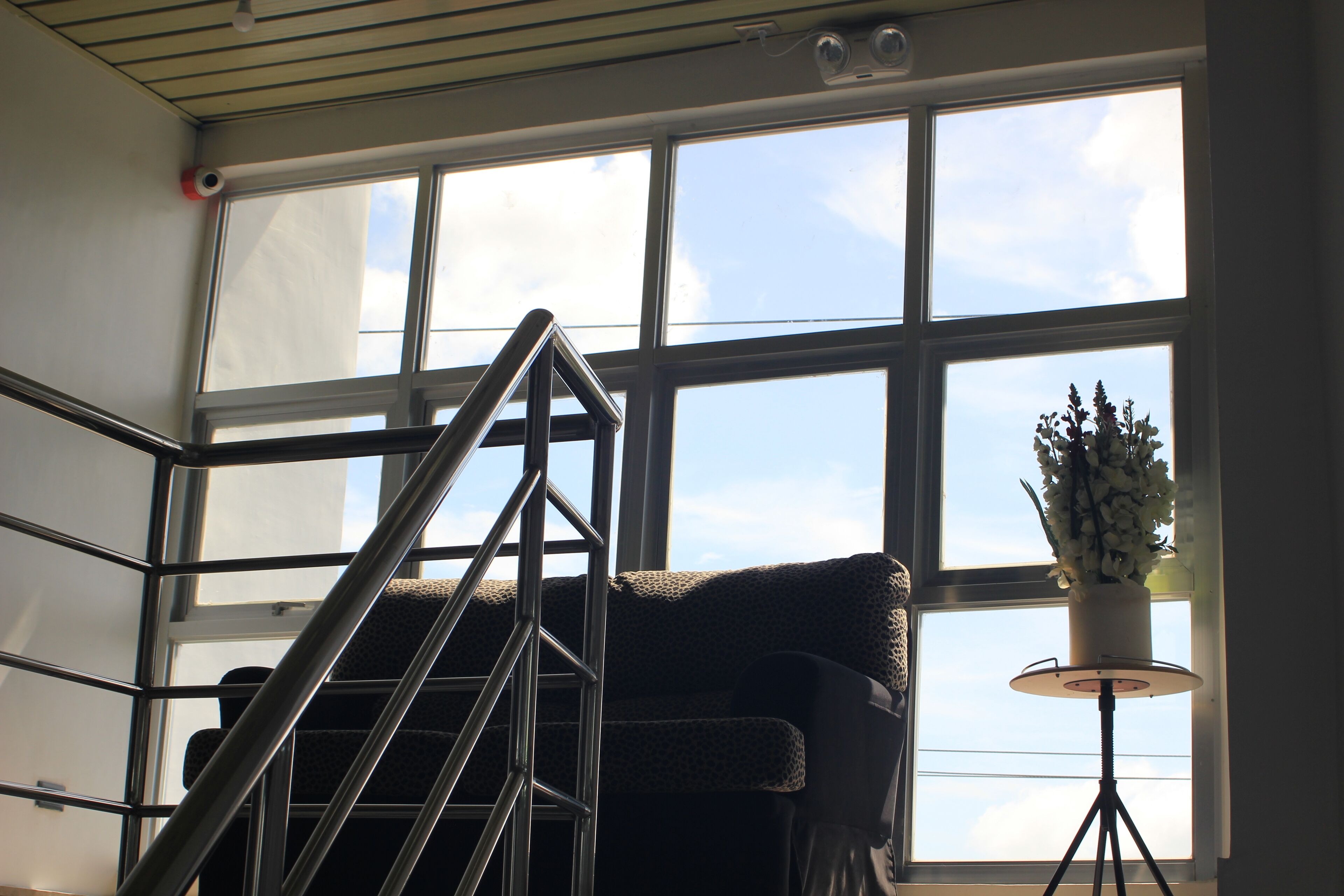 A staircase with a metal railing leading to a window with multiple panes.