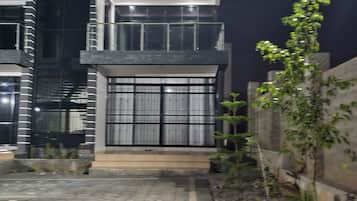 Stunning two-story building with a glass facade and balconies, set amidst a beautifully landscaped garden.
