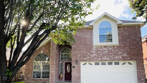 A two-story brick house with a garage, large windows, and a well-maintained lawn. - 5BR Near AT&T Stadium Lakefront Sleeps 10 Best Lake Views at Irving Lake (Irving)