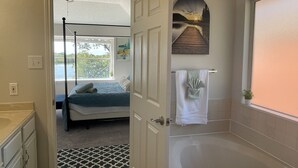 A bathroom with a bathtub, a shower, and a window with a view of a dock and sunset. - 5BR Near AT&T Stadium Lakefront Sleeps 10 Best Lake Views at Irving Lake (Irving)