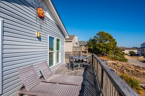 A deck with wooden furniture, a sun decoration, and a house with a light blue exterior.