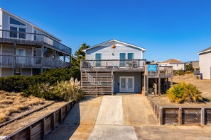 A two-story house with a balcony, a garage, and a wooden deck.