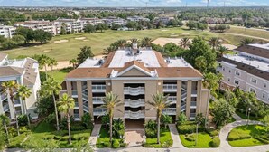 A multi-story hotel with a central courtyard, surrounded by lush greenery and palm trees.