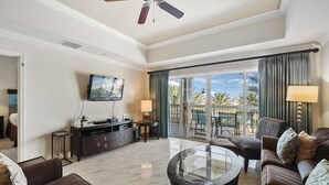 A spacious living room with a flat-screen TV, a glass coffee table, and a sofa.